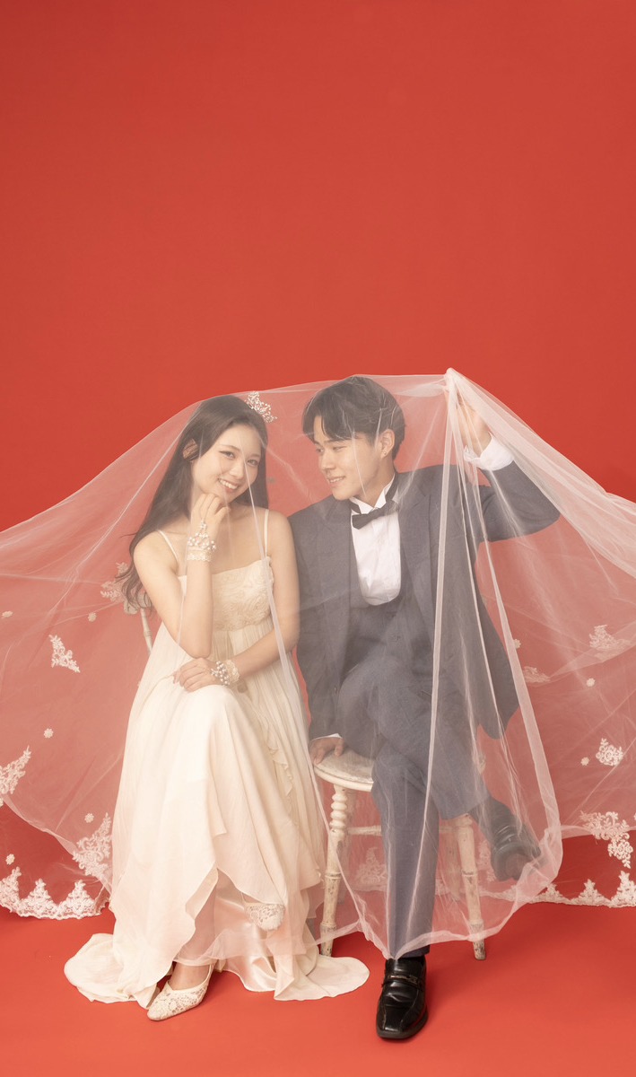赤い背景でベールをかぶったカップルの結婚写真前撮り